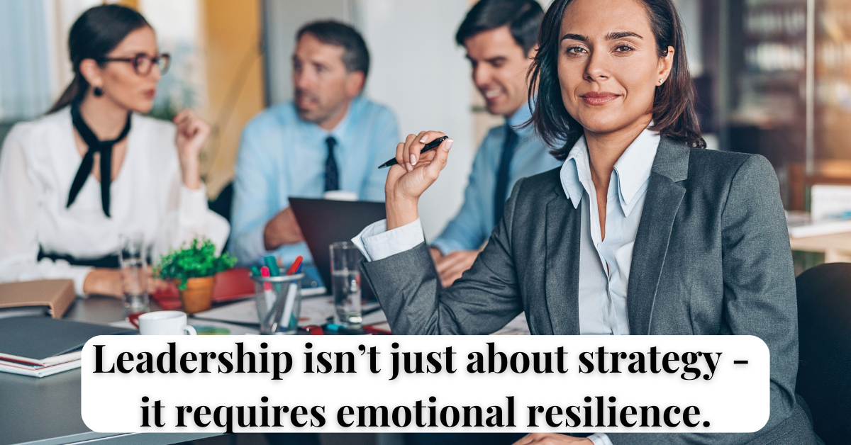 Professional woman leader sitting at desk with team in background, representing the emotional complexity of leadership.
