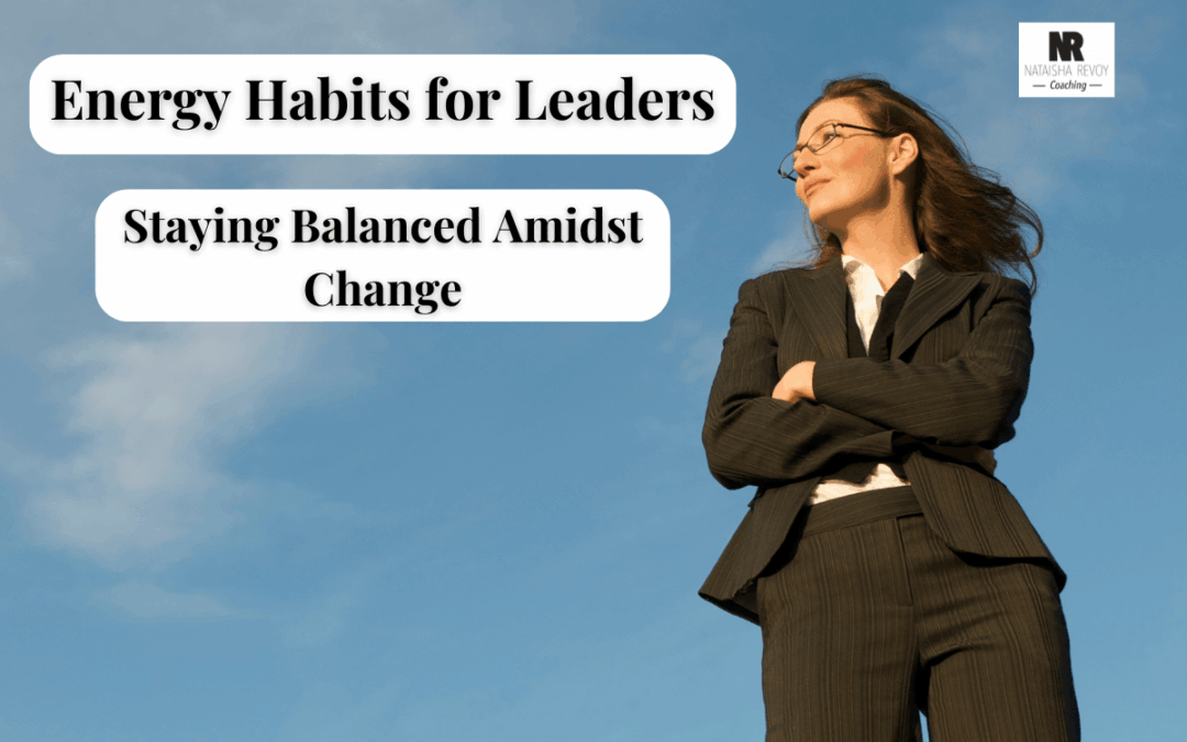 Confident businesswoman in a suit standing outdoors under a clear blue sky with text overlay: ‘Energy Habits for Leaders – Staying Balanced Amidst Change.’