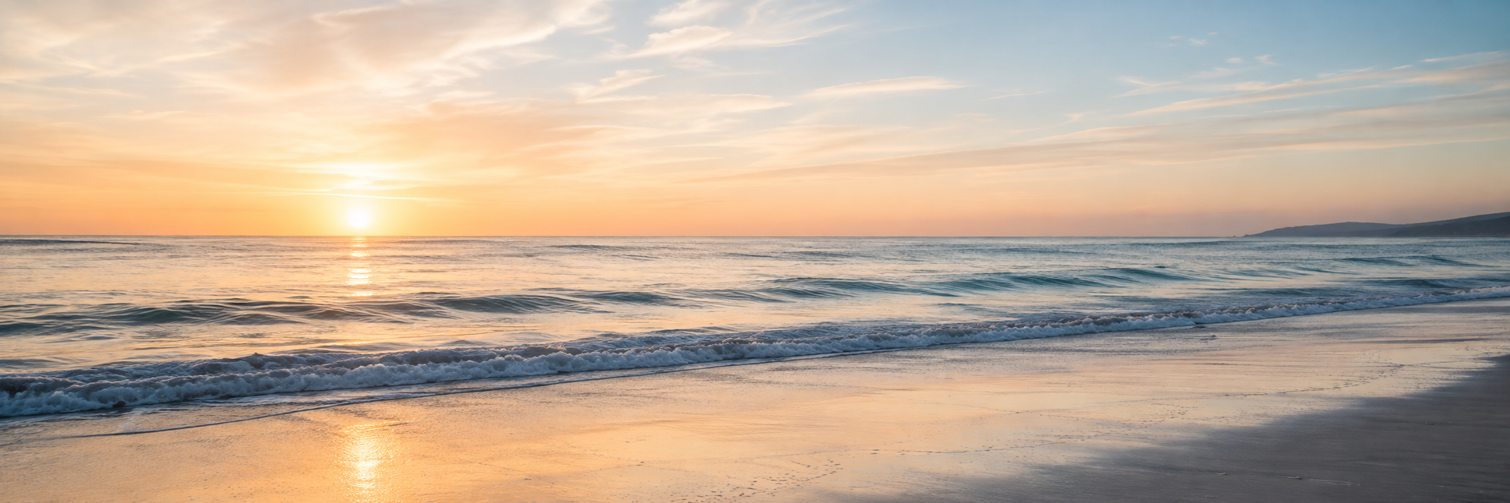 A peaceful ocean horizon at sunrise with gentle waves rolling onto a quiet sandy shoreline beneath soft pastel skies.