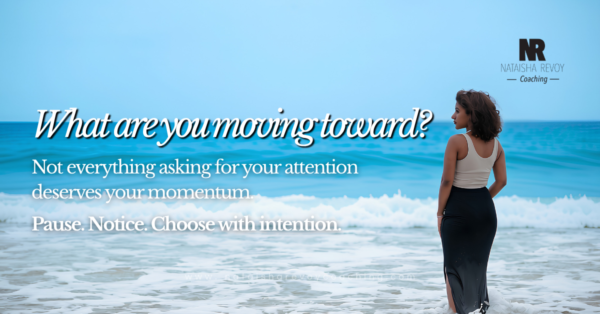 A woman with curly brown hair stands facing away from the camera on a beach, looking out at turquoise ocean waves. She wears a beige tank top and a long black skirt with a side slit. Overlaid text reads "What are you moving toward? Not everything asking for your attention deserves your momentum. Pause. Notice. Choose with intention." 